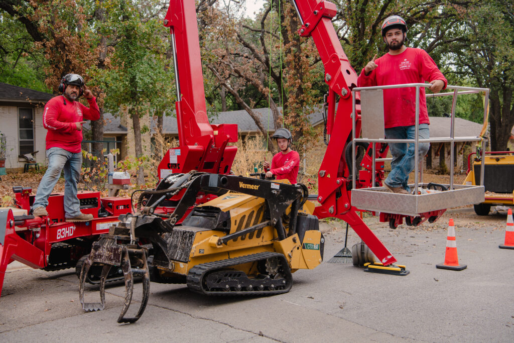 three men from clean edge tree service standing on tree removal equipment in denton